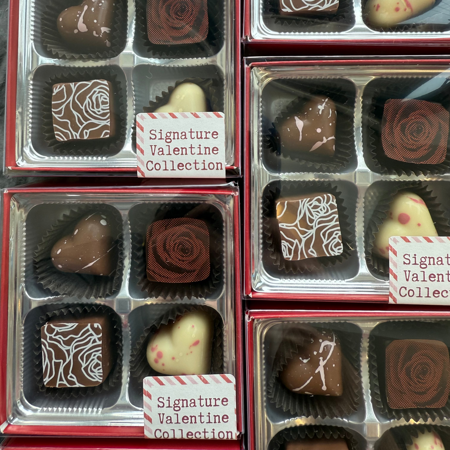Collection of Valentine's Day chocolates in clear packaging with decorative designs.